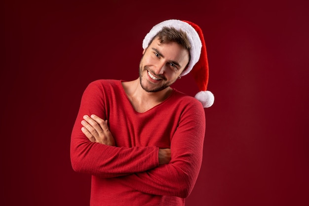 Jovem bonitão na camisola vermelha e chapéu de Papai Noel