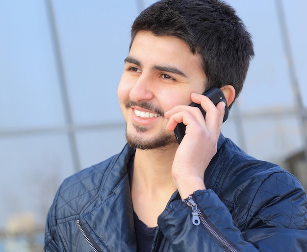 jovem bonito à paisana, falando ao telefone.