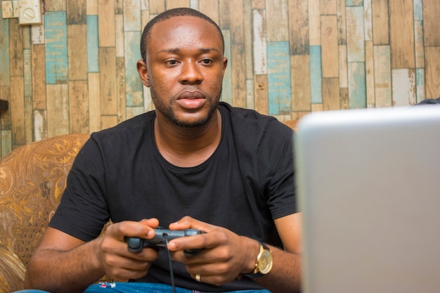 Jovem bonito africano jogando sério em seu laptop