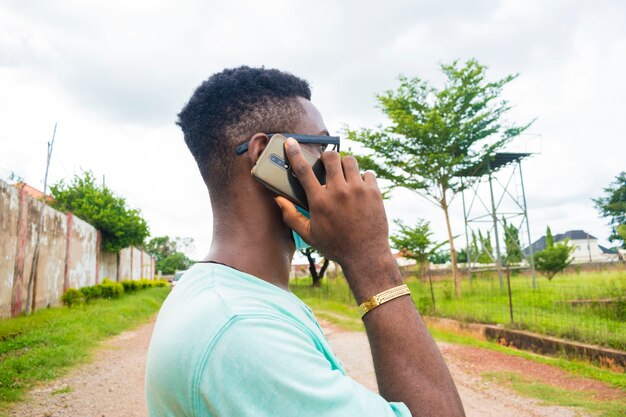 Jovem bonito africano usando máscara facial fazendo chamadas com seu celular.