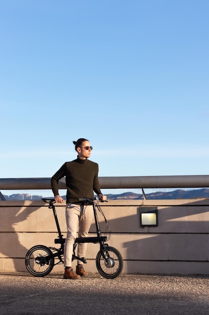 Jovem bonito andando de bicicleta elétrica como uma alternativa sustentável e ecológica para passear pela cidade