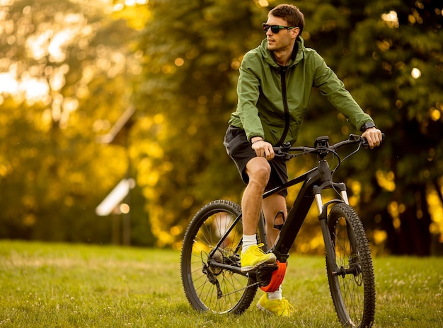 Jovem bonito andando de ebike no parque