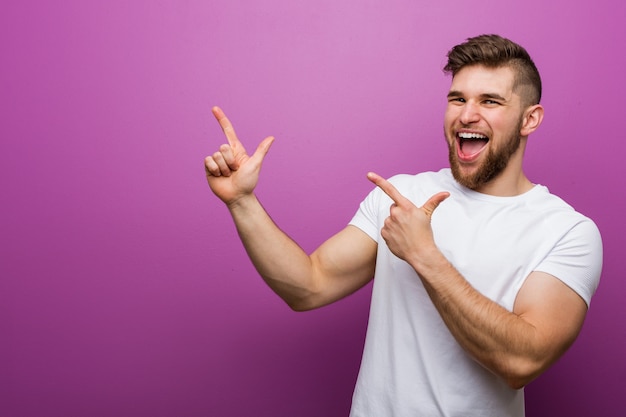 Jovem bonito apontando com o dedo indicador e expressando emoção e desejo