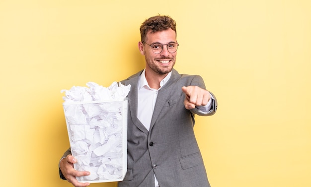 Jovem bonito apontando para a câmera escolhendo o conceito de lixo de bolas de papel