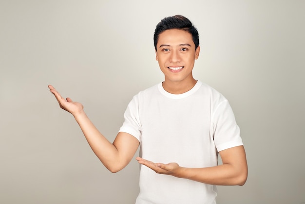 Jovem bonito apontando para o lado com a mão e a palma da mão aberta apresentando anúncio sorrindo feliz e confiante