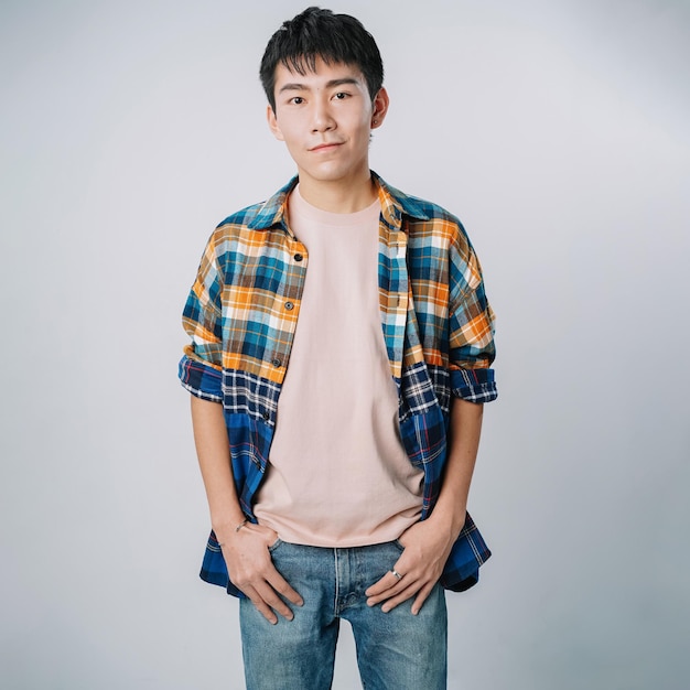 Jovem bonito asiático flanela camiseta jeans sorrindo em pé isolado parede cinza