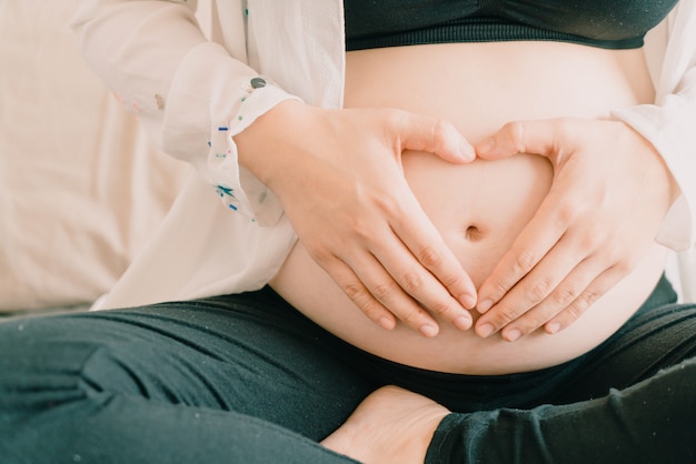 Jovem, bonito, asiático, mulher grávida, segurando, dela, mãos, em, um, forma coração, ligado, barriga grávida