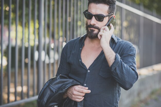 jovem bonito atraente modelo de barba homem usando smartphone