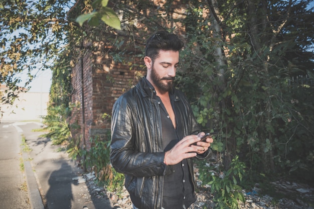 Jovem bonito atraente modelo de barba homem usando smartphone