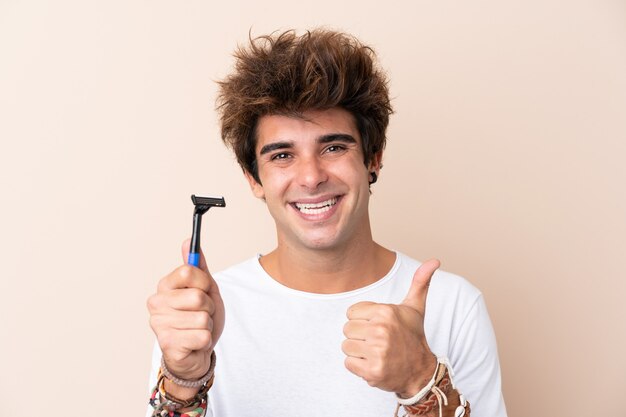 Jovem bonito barbear a barba com polegares para cima porque algo bom aconteceu