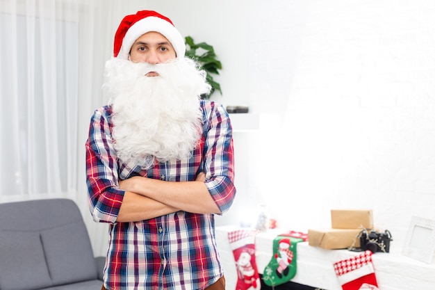 jovem bonito barbudo homem de papai noel com barba comprida e chapéu de ano novo, fundo de natal