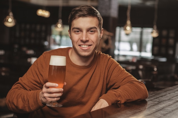Jovem bonito bebendo cerveja no bar