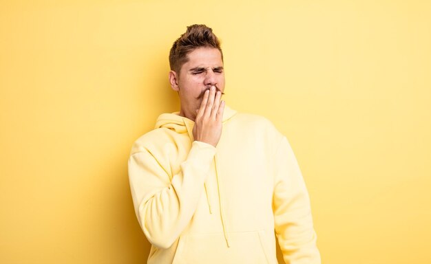 Jovem bonito bocejando preguiçosamente no início da manhã acordando e parecendo sonolento, cansado e entediado conceito de bigode estranho