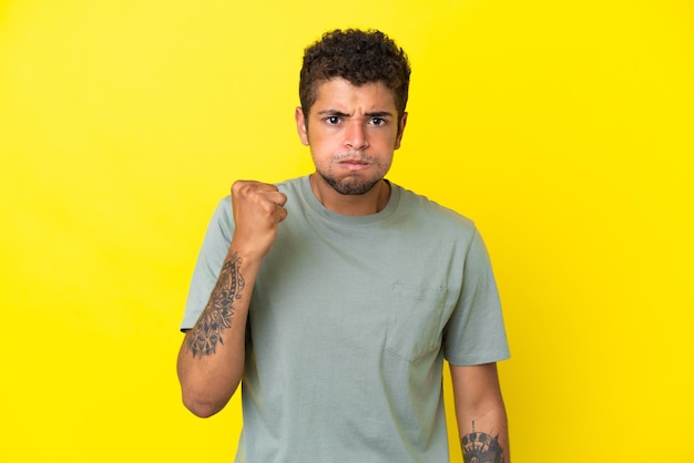 Foto jovem bonito brasileiro isolado em um fundo amarelo com expressão infeliz