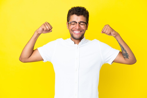 Jovem bonito brasileiro isolado em um fundo amarelo fazendo um gesto forte