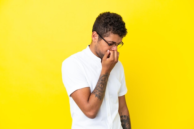 Foto jovem bonito brasileiro isolado em um fundo amarelo tendo dúvidas