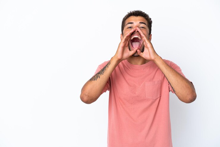 Foto jovem bonito brasileiro isolado no fundo branco gritando e anunciando algo