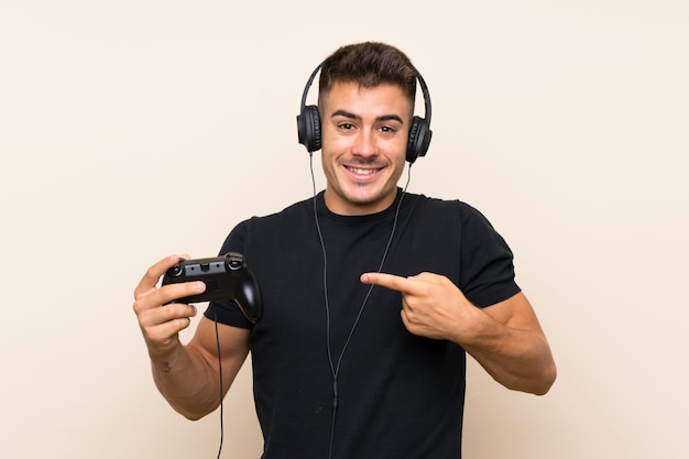 Jovem bonito, brincando com um controlador de videogame com expressão facial de surpresa