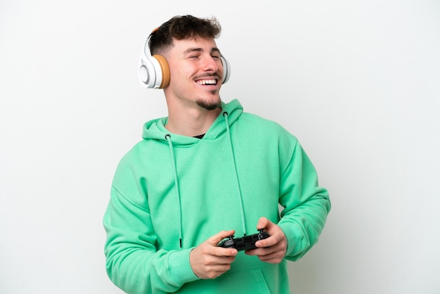 Jovem bonito brincando com um controlador de videogame isolado no fundo branco rindo