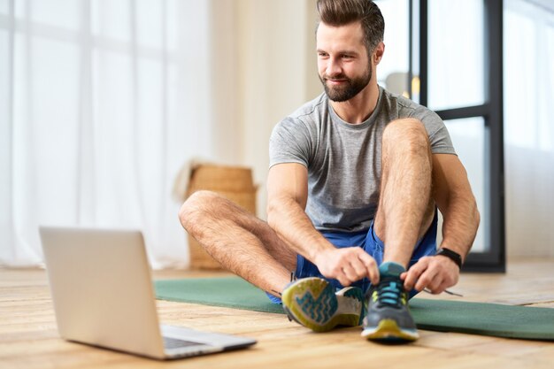 Jovem bonito calçando tênis e usando laptop