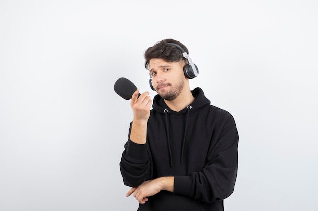 Jovem bonito cantando karaokê com grandes fones de ouvido sem fio