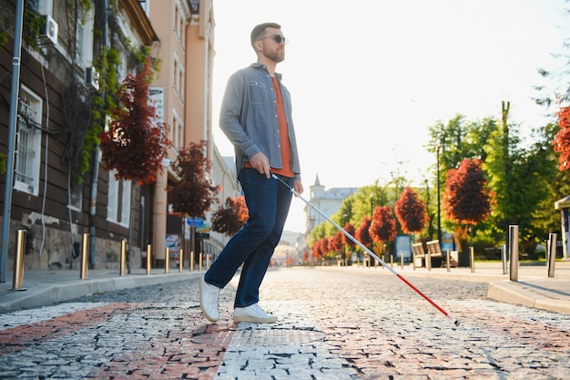 Jovem bonito cego andando com vara na cidade