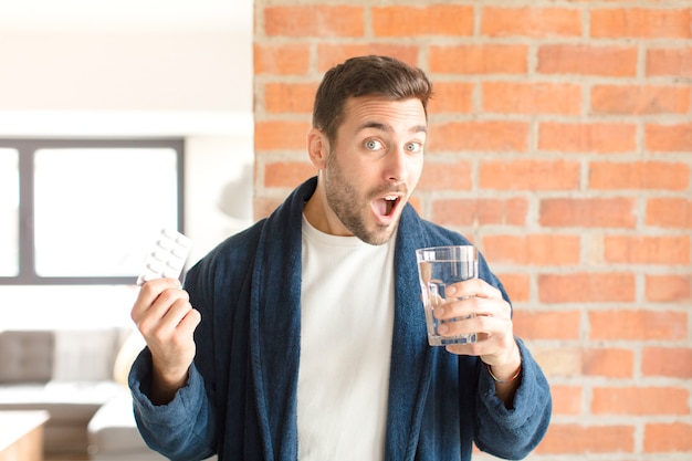 Jovem bonito com água e comprimidos