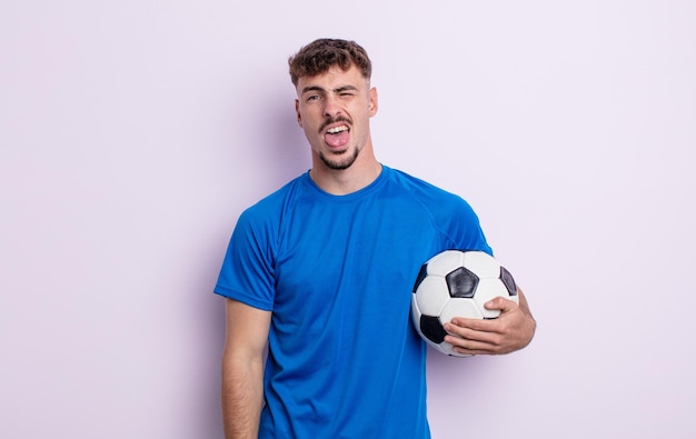 Jovem bonito com atitude alegre e rebelde, brincando e mostrando a língua. conceito de futebol