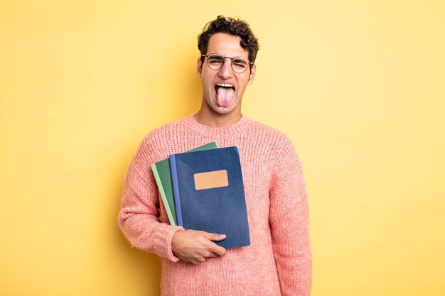 Jovem bonito com atitude alegre e rebelde, brincando e mostrando a língua. conceito de notebook