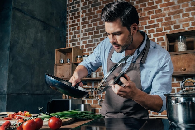 Jovem bonito com avental de cozinha