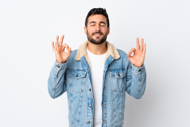 Jovem bonito com barba isolada na parede branca em pose de zen