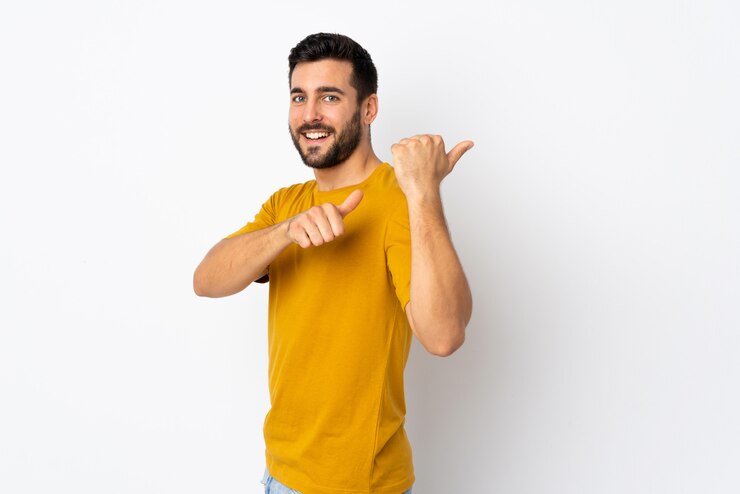 Foto jovem bonito com barba isolada no branco, apontando para o lado para apresentar um produto