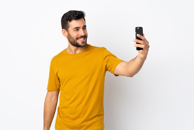 Jovem bonito com barba isolada no fundo branco fazendo uma selfie