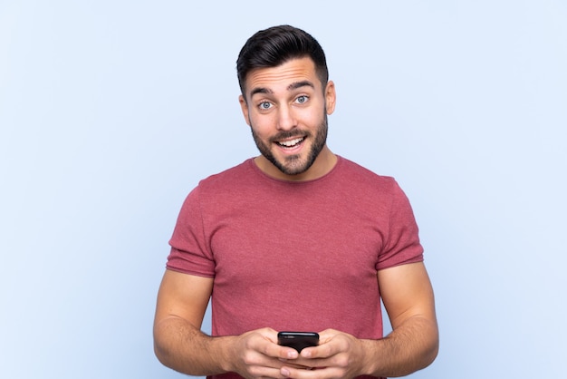 Jovem bonito com barba isolado surpreso e mandando uma mensagem