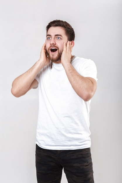 Jovem bonito com barba na camiseta ouvindo música nos fones de ouvido