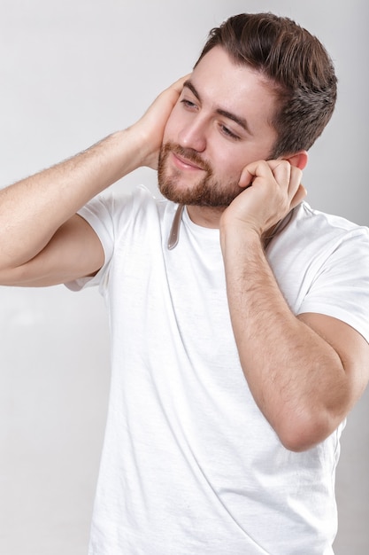 Jovem bonito com barba na camiseta ouvindo música nos fones de ouvido