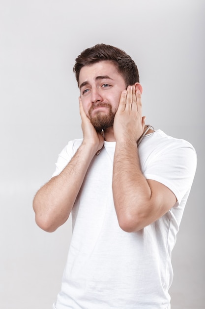 Jovem bonito com barba na camiseta ouvindo música nos fones de ouvido