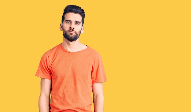 Jovem bonito com barba vestindo camiseta casual relaxado com expressão séria no rosto simples e natural olhando para a câmera