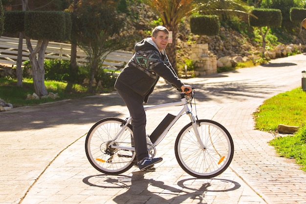Foto jovem bonito com bicicleta no parque em dia ensolarado