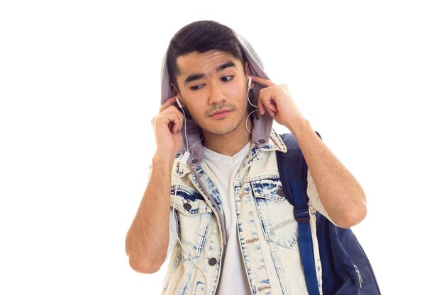 Jovem bonito com cabelo preto com mochila azul usando fones de ouvido e cantando