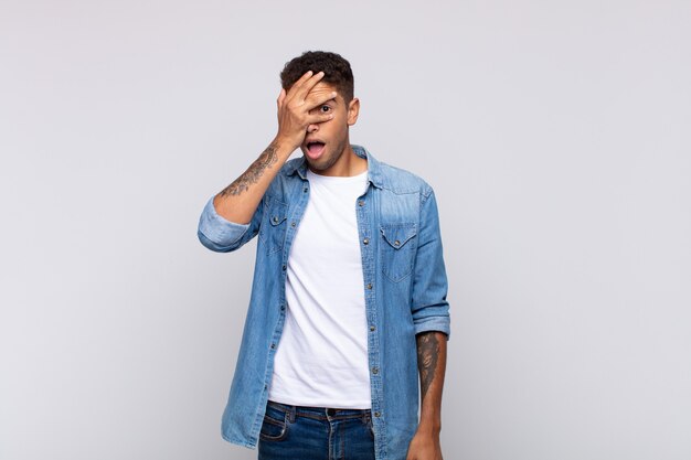 jovem bonito com camisa jeans posando na parede branca