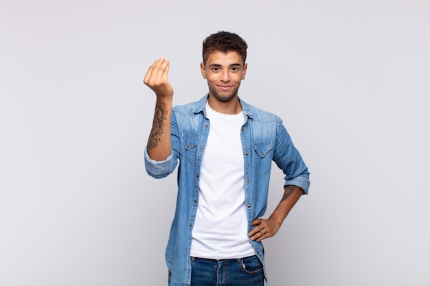 jovem bonito com camisa jeans posando na parede branca