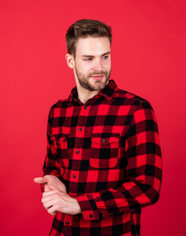 Foto jovem bonito com camisa quadriculada vermelha. homens elegantes usam roupas casuais. homem barbudo com cerdas no rosto com a barba por fazer. moda e beleza. conceito de barbearia. desgaste dos homens.