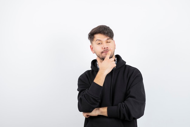 Jovem bonito com capuz preto usando grandes fones de ouvido de música sem fio