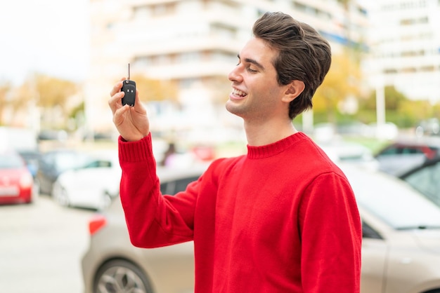 Jovem bonito com chave de carro com expressão feliz