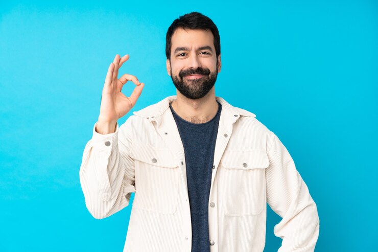 Foto jovem bonito com jaqueta de veludo branco sobre azul mostrando sinal de ok com os dedos