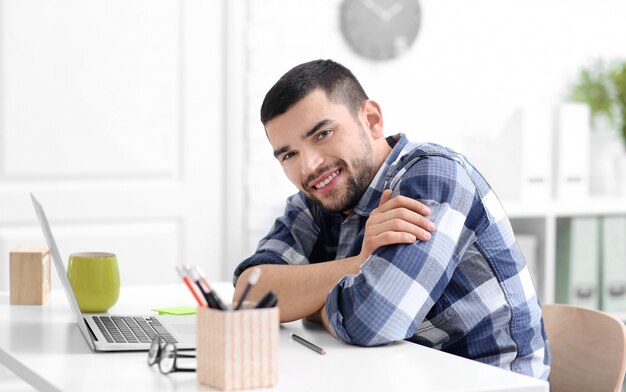 Jovem bonito com laptop na mesa