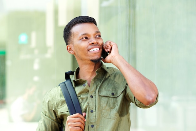 Jovem bonito com mochila falando no celular