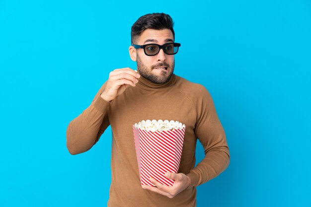 Foto jovem bonito com óculos 3d e segurando um grande balde de pipocas