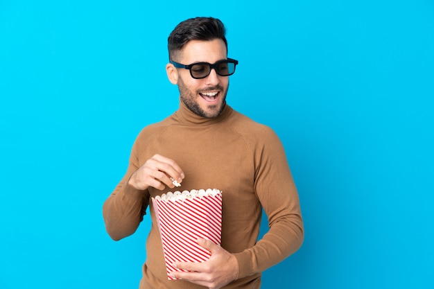 Jovem bonito com óculos 3d e segurando um grande balde de pipocas